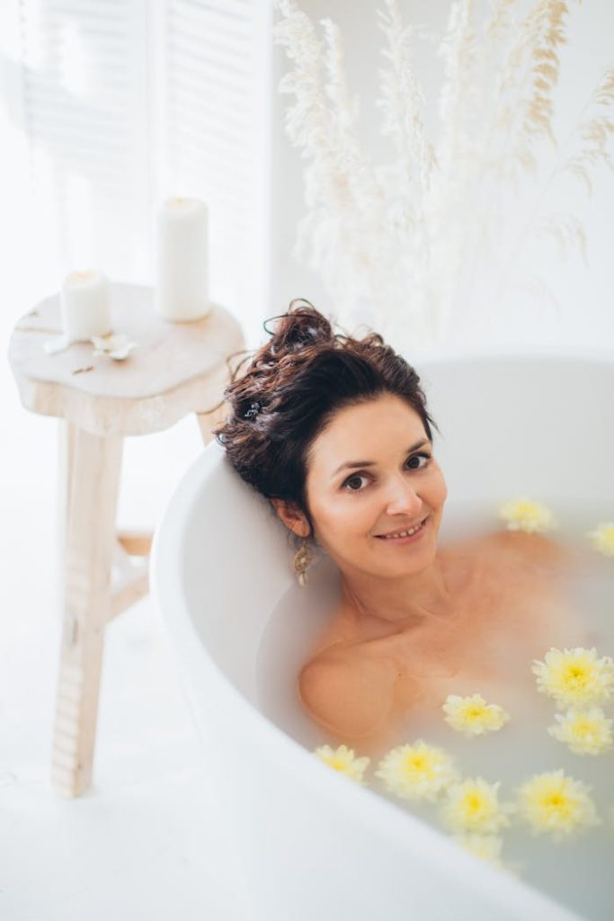 A woman relaxing in a milk bath with floating flowers, creating a peaceful and serene spa atmosphere.